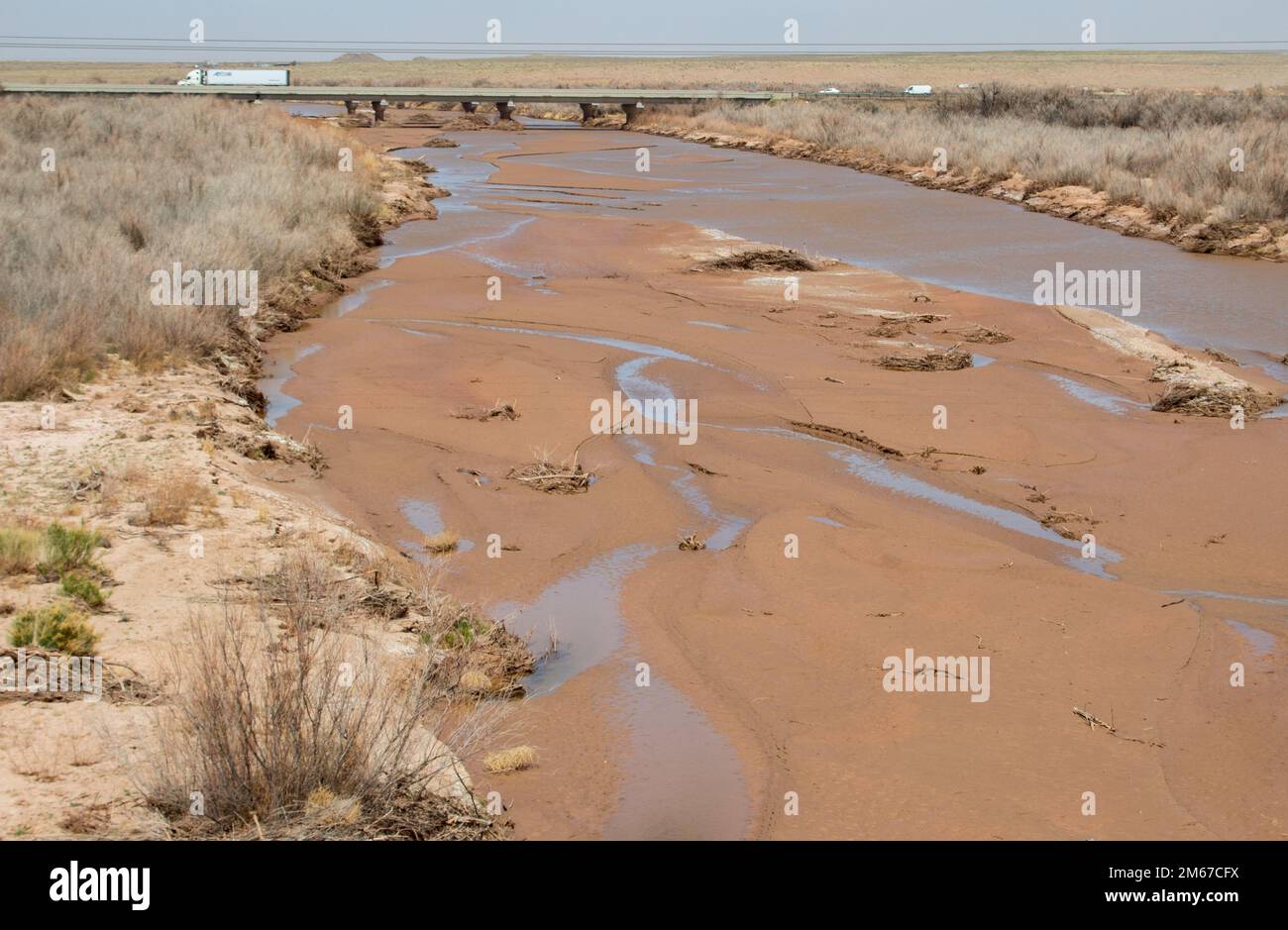 The Little Colorado River flows underneath bridges at mile marker 345 April 11 in Winslow, Ariz. Salt cedar, an invasive plant species along the banks and riverbed, increases the chance and severity of fires and floods in Navajo County. Stock Photo