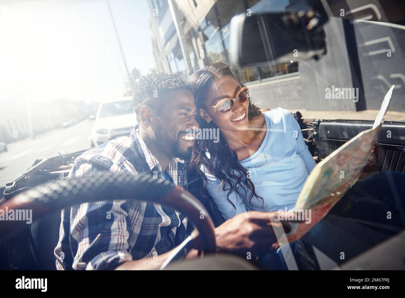 The world is ours. a young couple reading a map while sitting in the car. Stock Photo