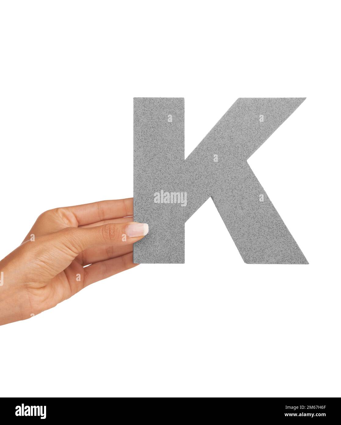 The letter K. A young woman holding a capital letter K isolated on a white background. Stock Photo