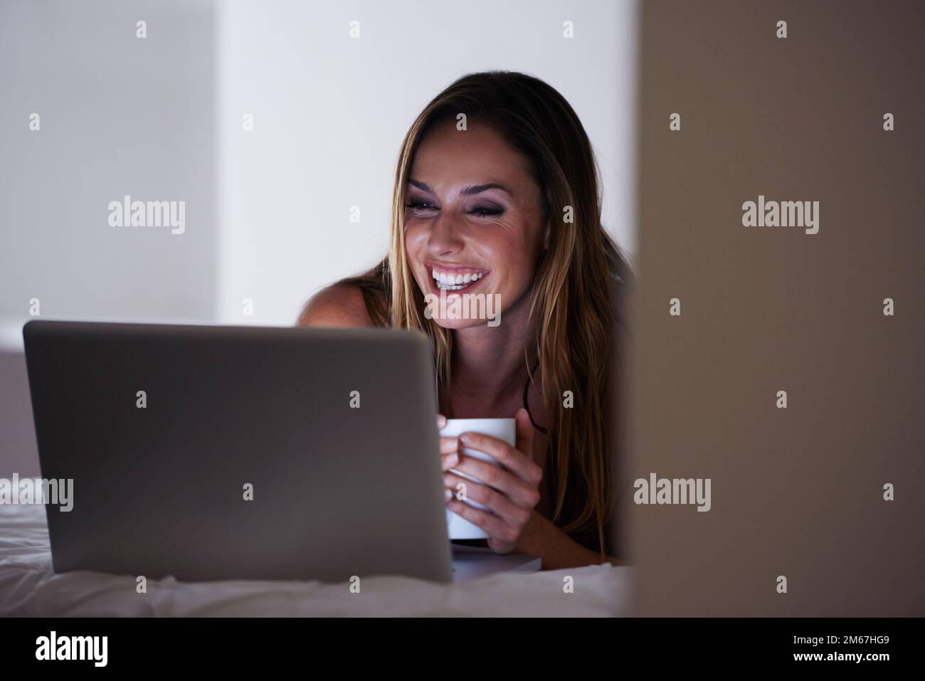 Connected from the comfort of home. A beautiful woman using her laptop from the comfort of her bed. Stock Photo