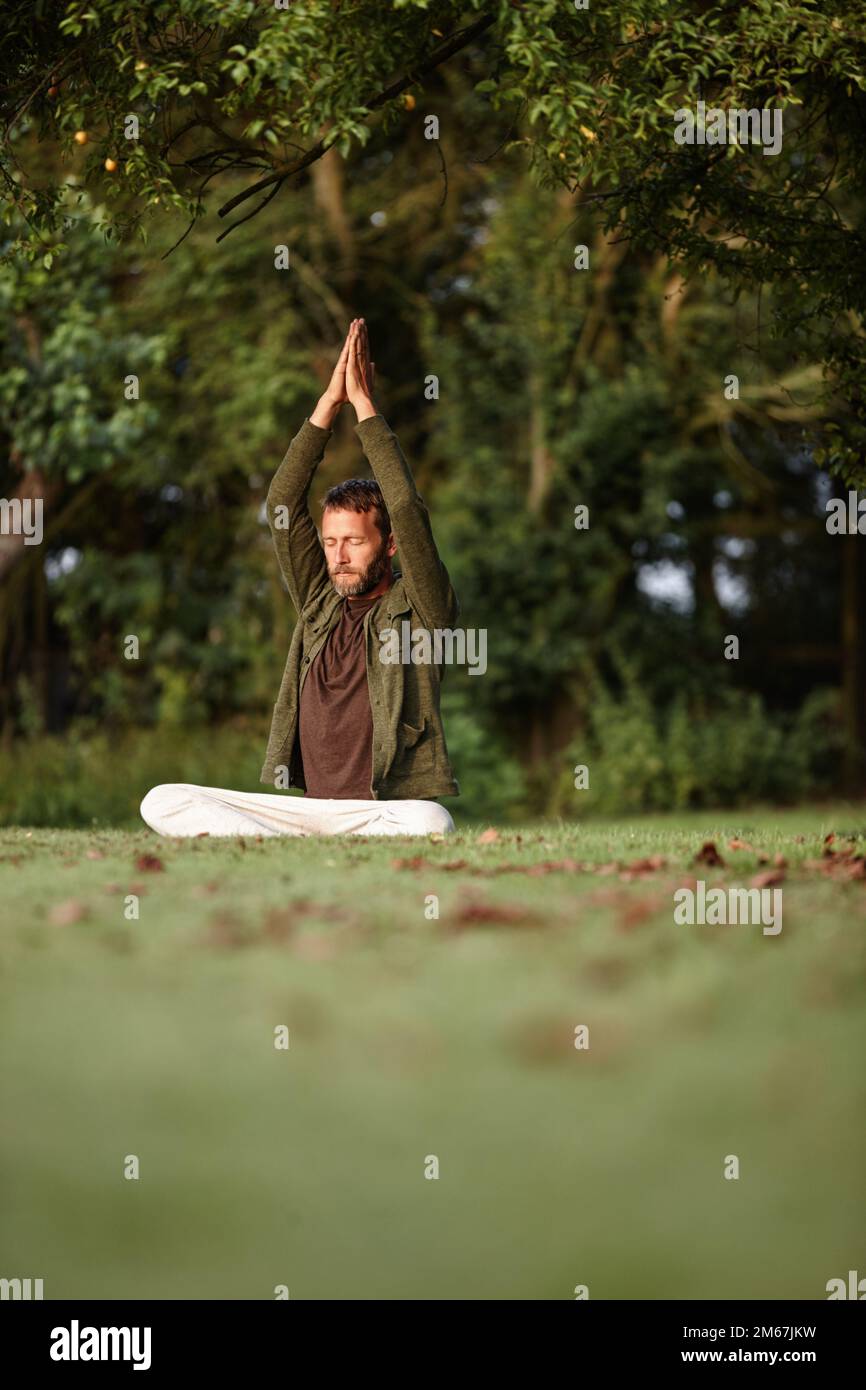 Reaching towards transcendence. a handsome mature man doing yoga in the outdoors. Stock Photo
