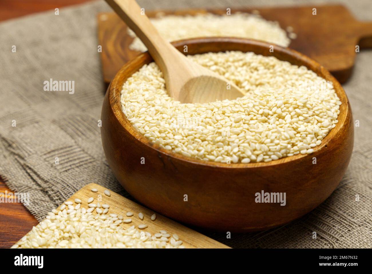 White sesame seeds in wooden bowl. Organic benne grains for healthy