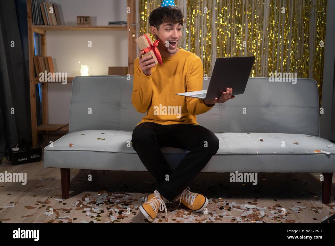 Guy holding birthday gift having video call via laptop, celebrating his
