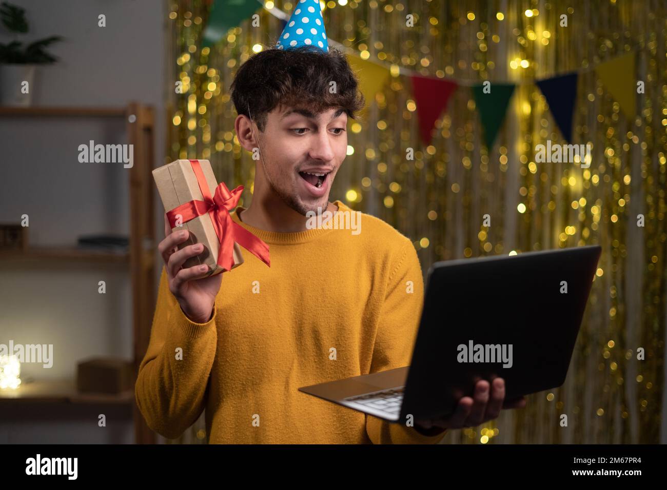 Guy holding birthday gift having video call via laptop, celebrating his