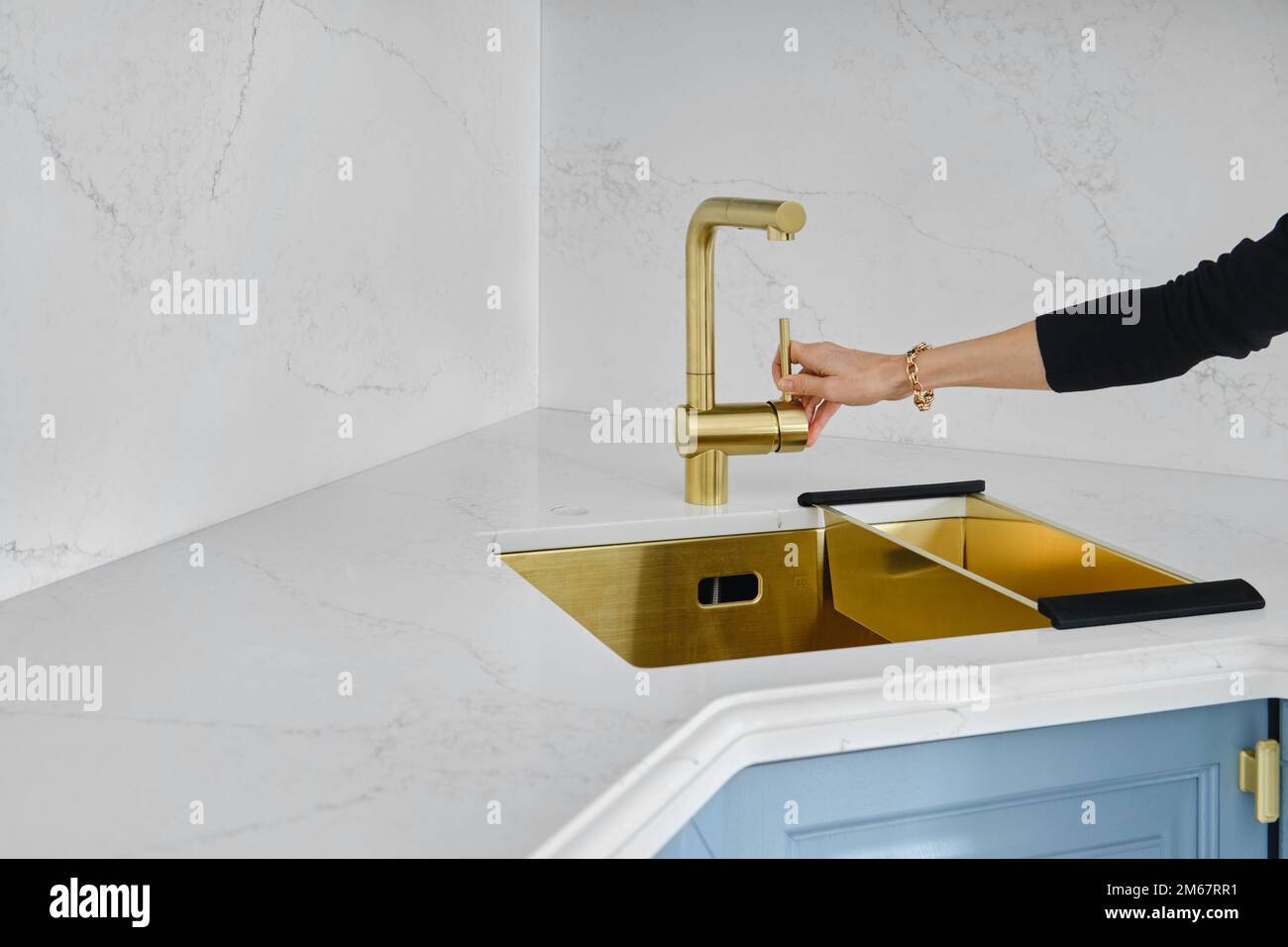 Female hand turns on the water in the sink in the kitchen. Concept of