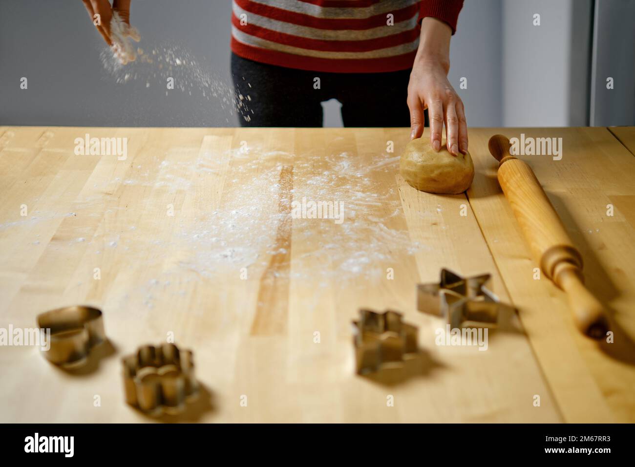 Unrecognizable woman sprinkles flour on table to roll out dough Stock Photo