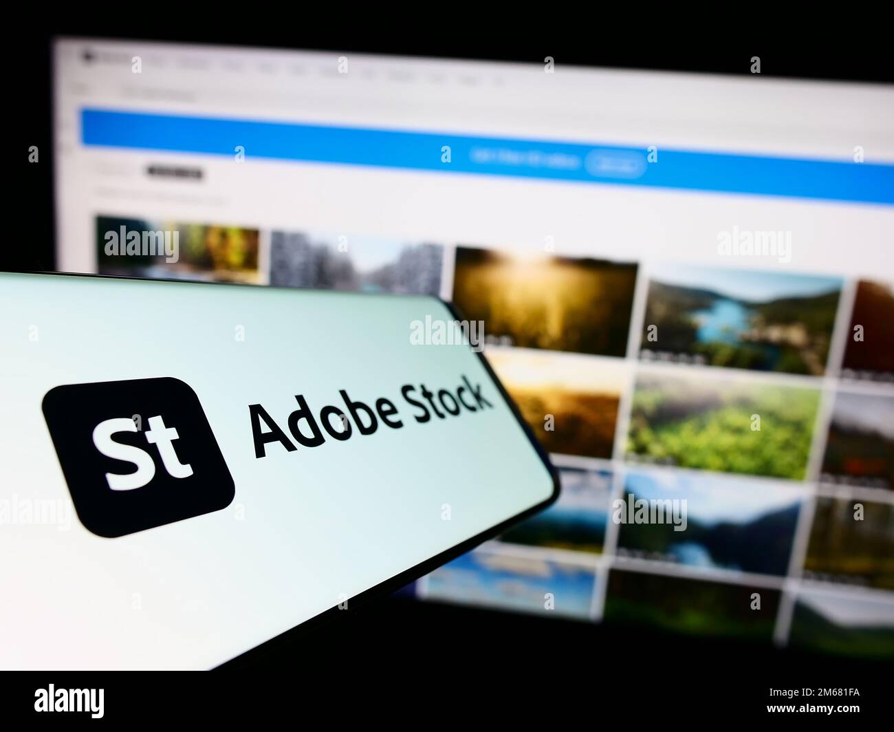 Cellphone with logo of American microstock agency Adobe Stock on screen in front of business website. Focus on center-left of phone display. Stock Photo