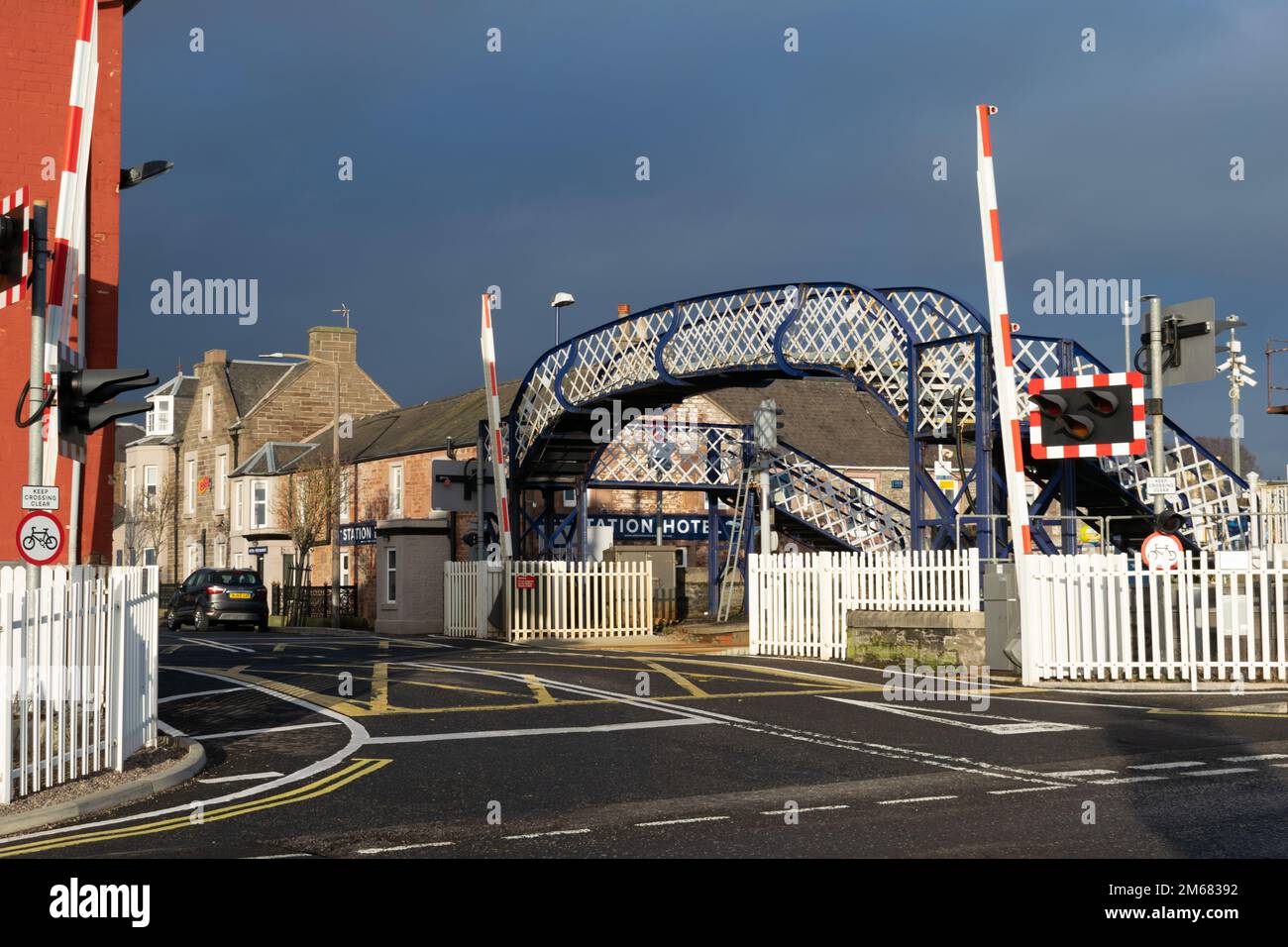 Carnoustie train station level crossing with barrier and footbridge over railway . Scotland UK. Stock Photo