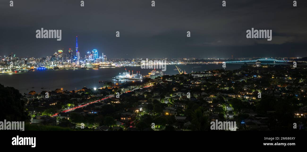 Panorama view of Auckland city at night, with Skytower on the left and Harbour bridge on the right of the image. Stock Photo
