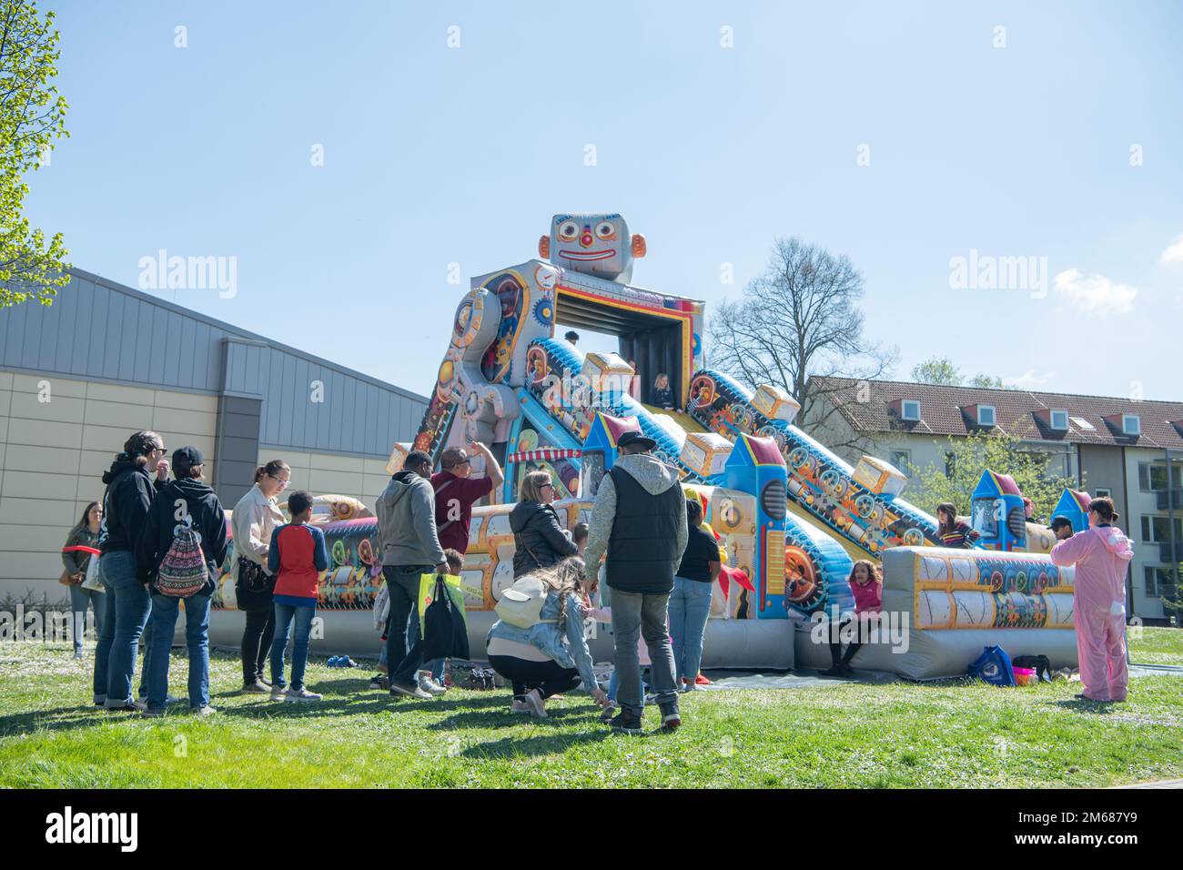 Wiesbaden parents and children stand in line for the inflatable slide at the Kinderfest event April 16, 2022, on Hainerberg Housing Area in Wiesbaden, Hessen, DE. The event featured a myriad of youth activities including face painting, bungy jumping, and carousel riding. Stock Photo