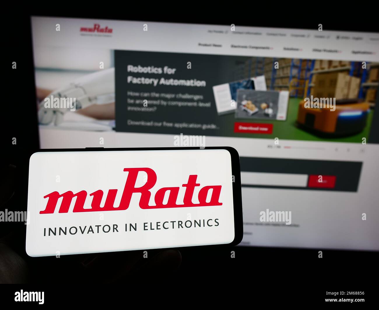 Person holding mobile phone with logo of Japanese company Murata Manufacturing Co. Ltd. on screen in front of web page. Focus on phone display. Stock Photo
