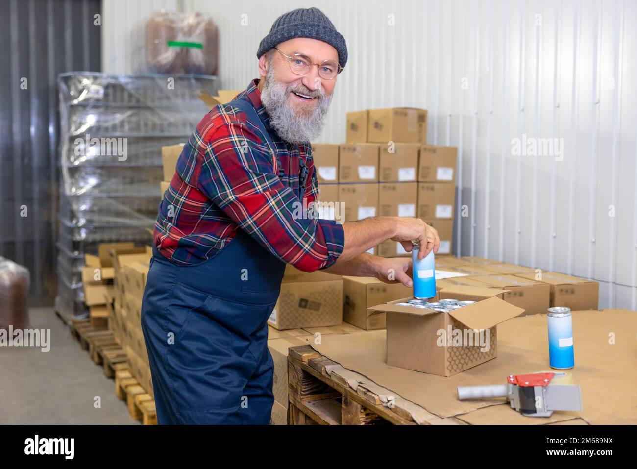 Cheerful man packing canned drinks for shipping Stock Photo Alamy