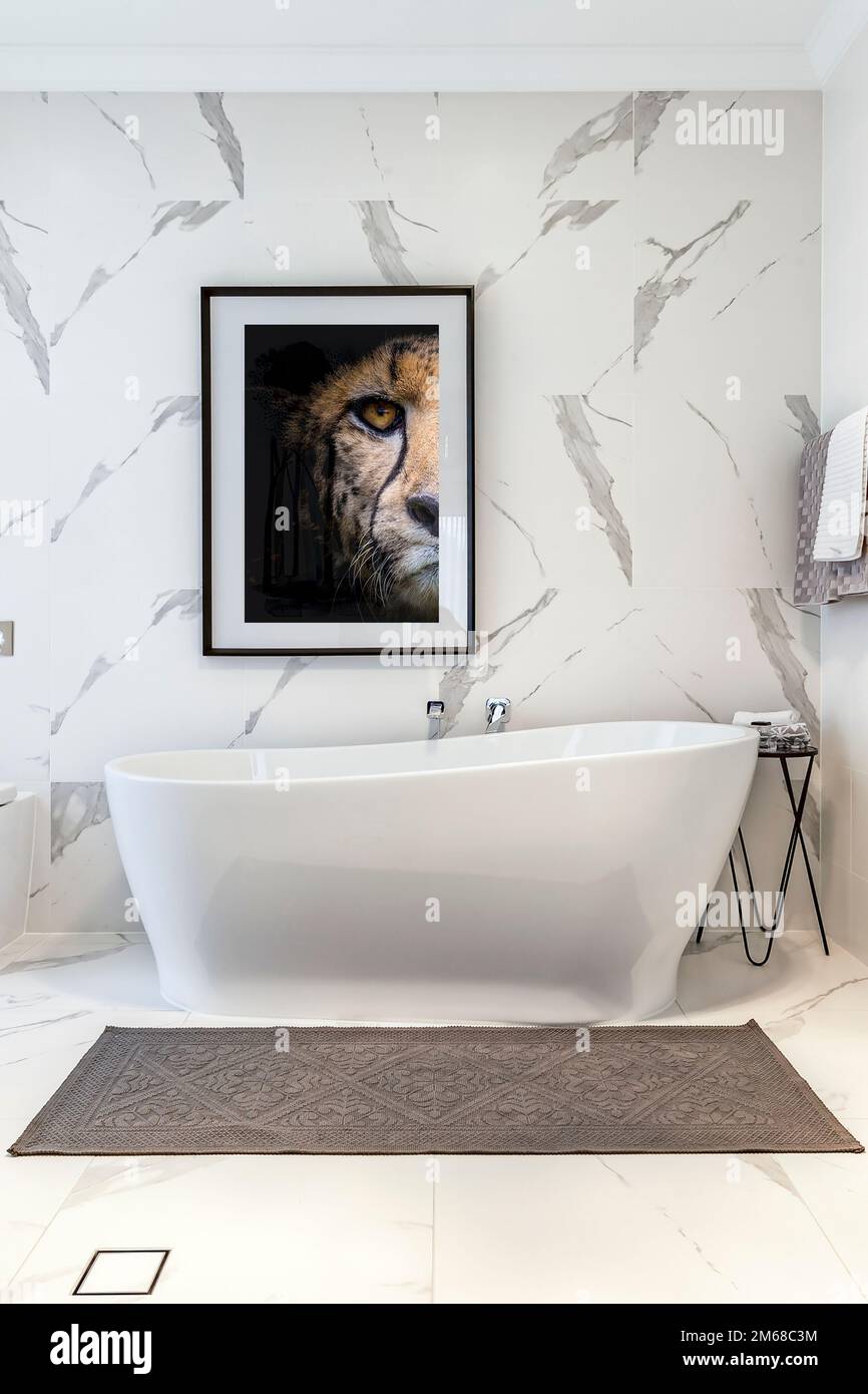 White tiled bathroom with floor to ceiling tiles with free standing bath Stock Photo Alamy