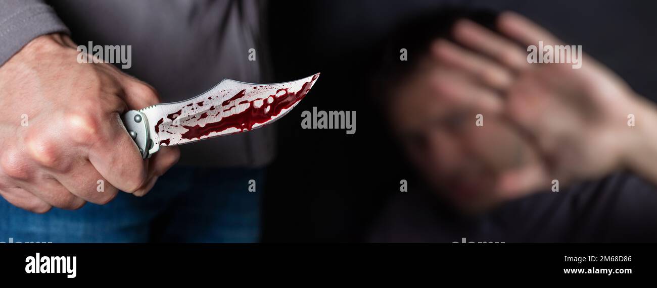 Close up of Hand with knife following young terrified man Bandit is holding a knife in hand. Threat Concept. Stock Photo