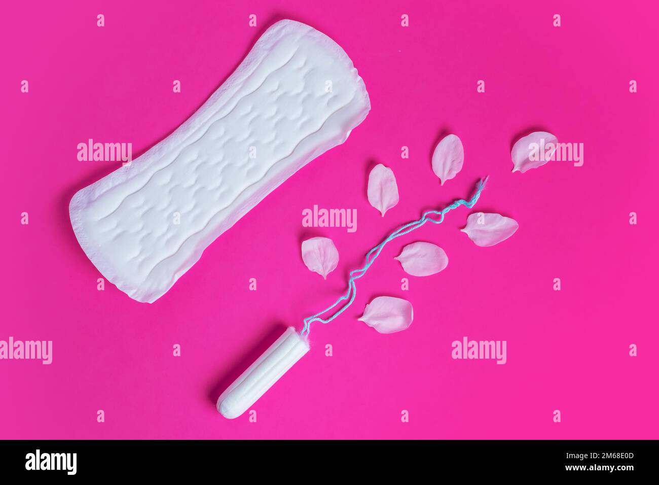 Female tampon with with cherry petals and woman gasket on a pink