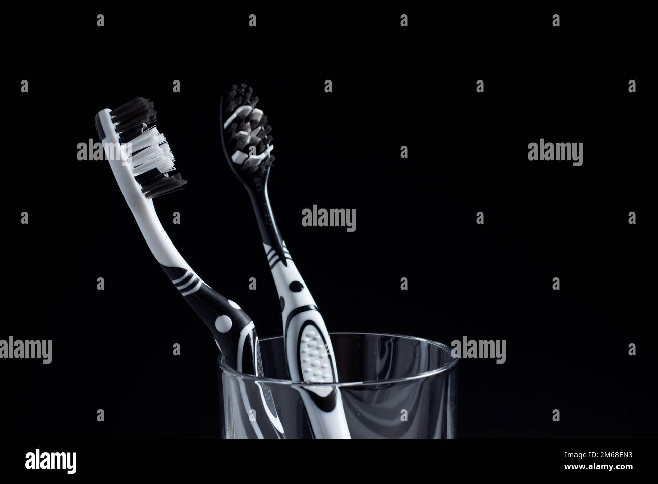Two toothbrushes in a glass with copy space on black Stock Photo - Alamy