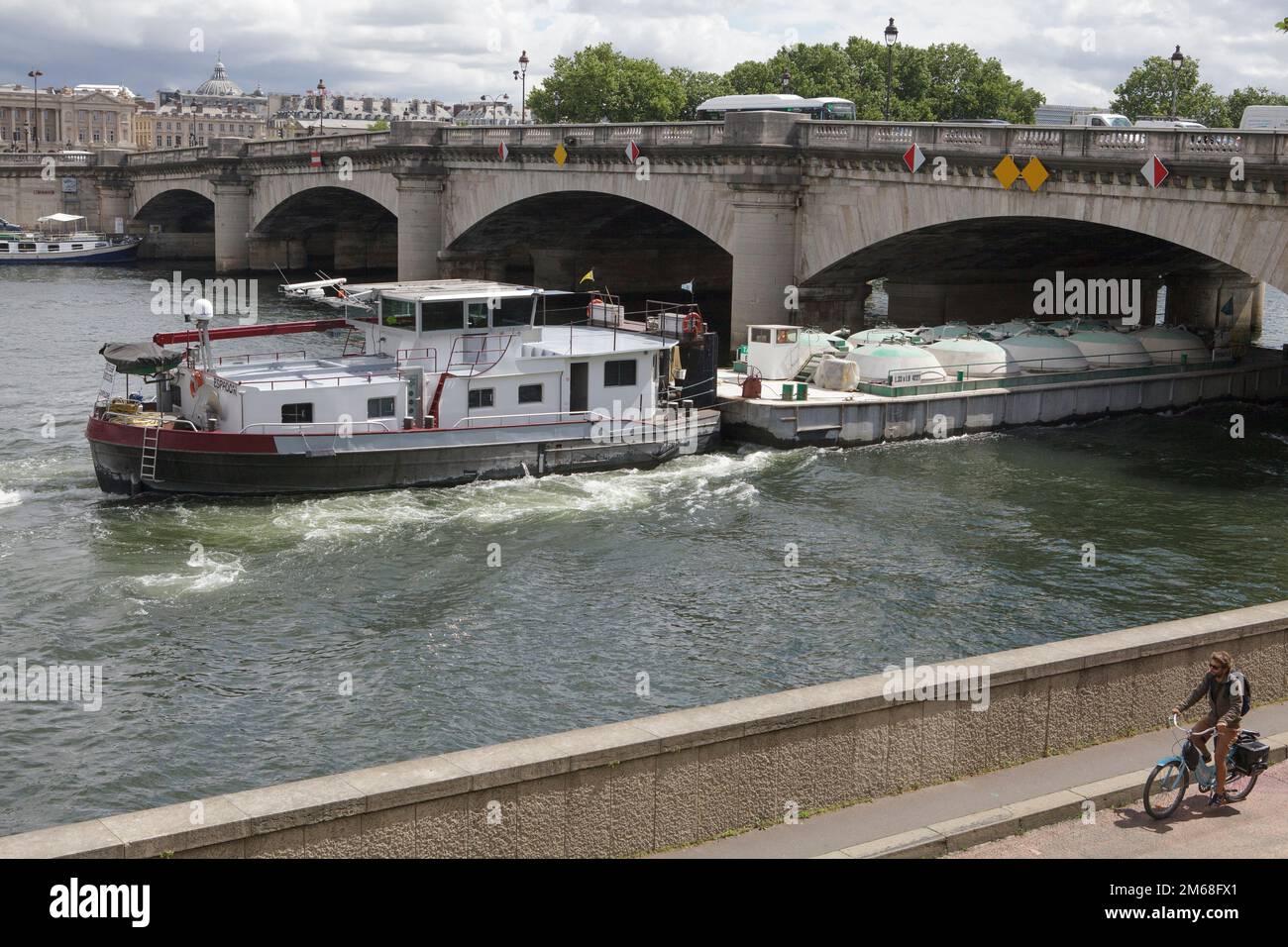 A barge passing under a bridge on the River Seine in the centre of Paris Stock Photo