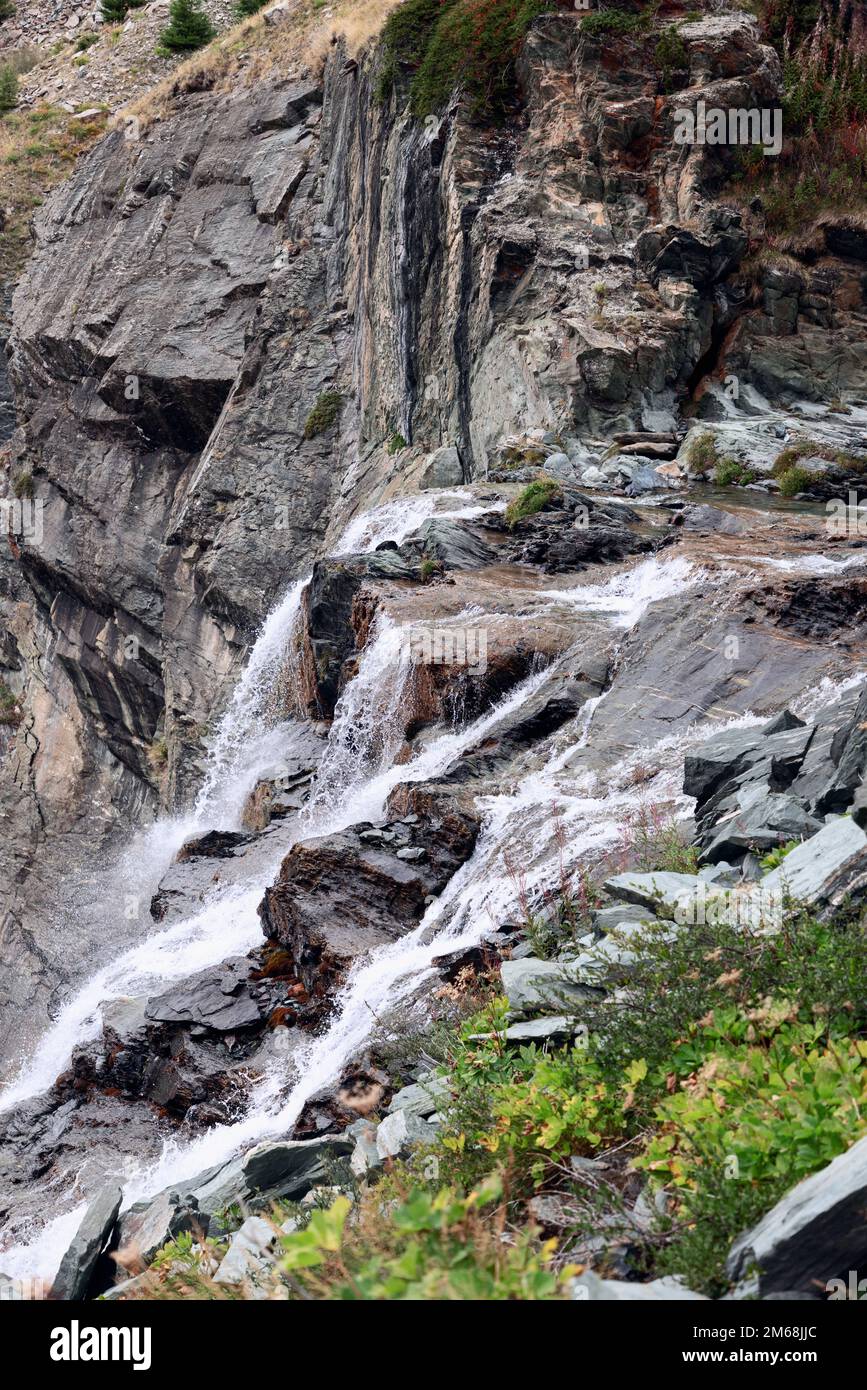 Foaming cascades of an alpine waterfall on granite rocks of various