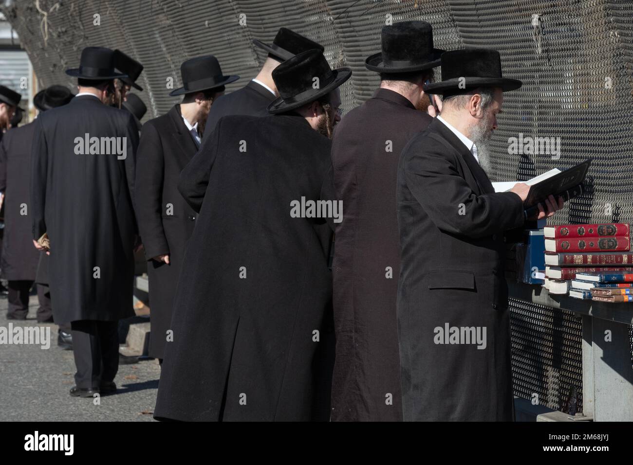A group of Hasidic orthodox jews browse religious books at a pop up