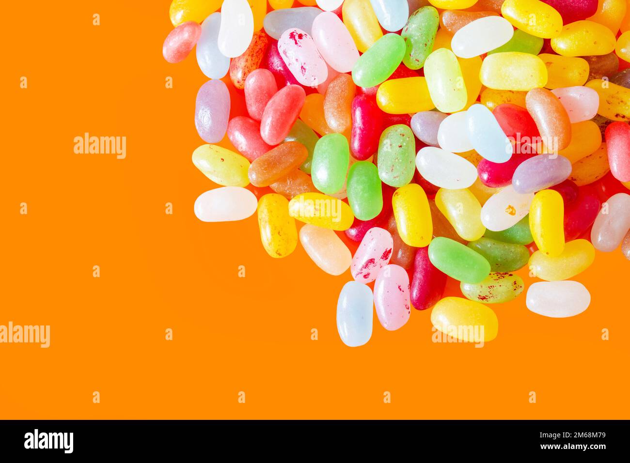 Jelly beans sweets candy piled on an orange background. High sugar