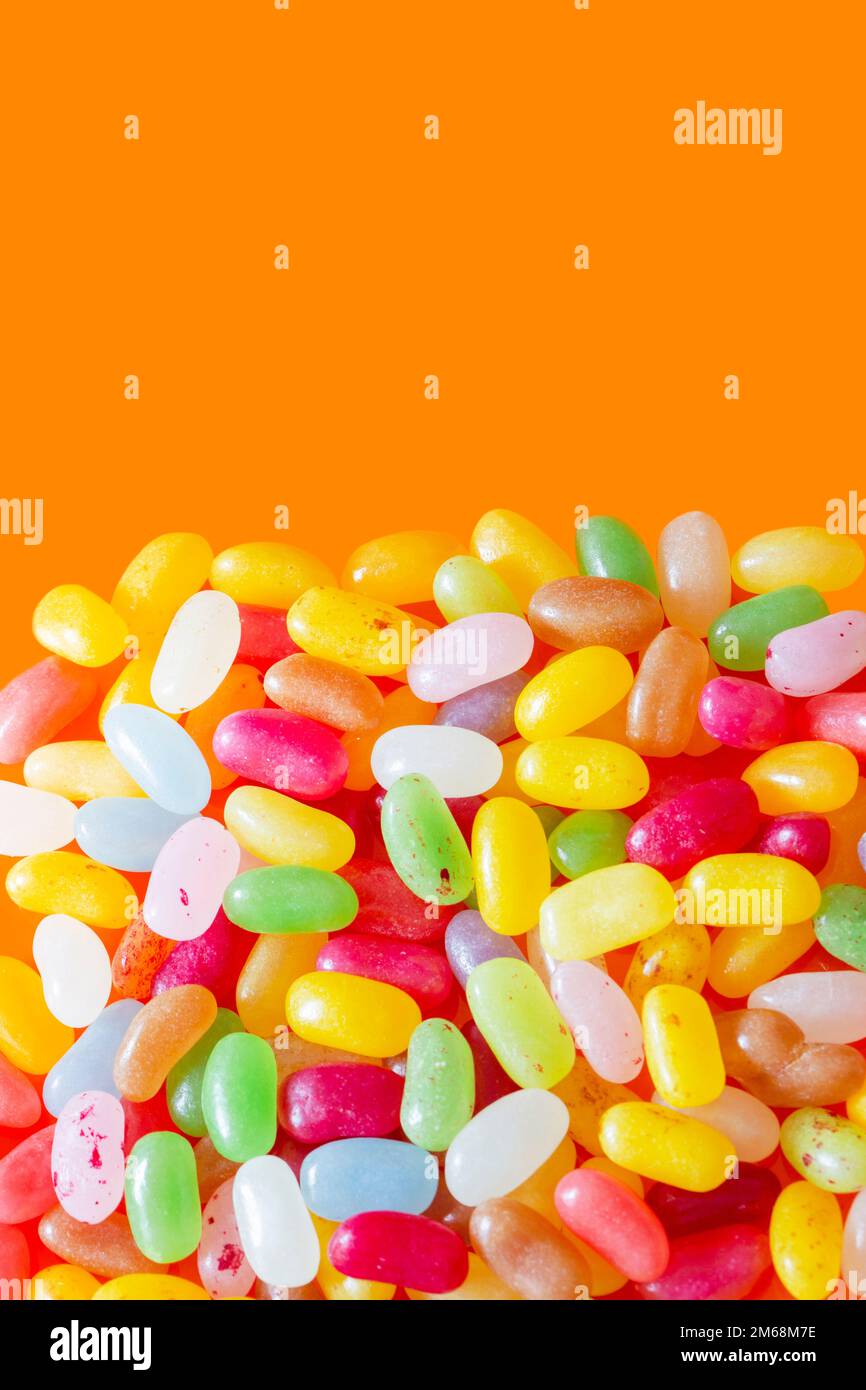 Jelly beans sweets candy piled on an orange background. High sugar
