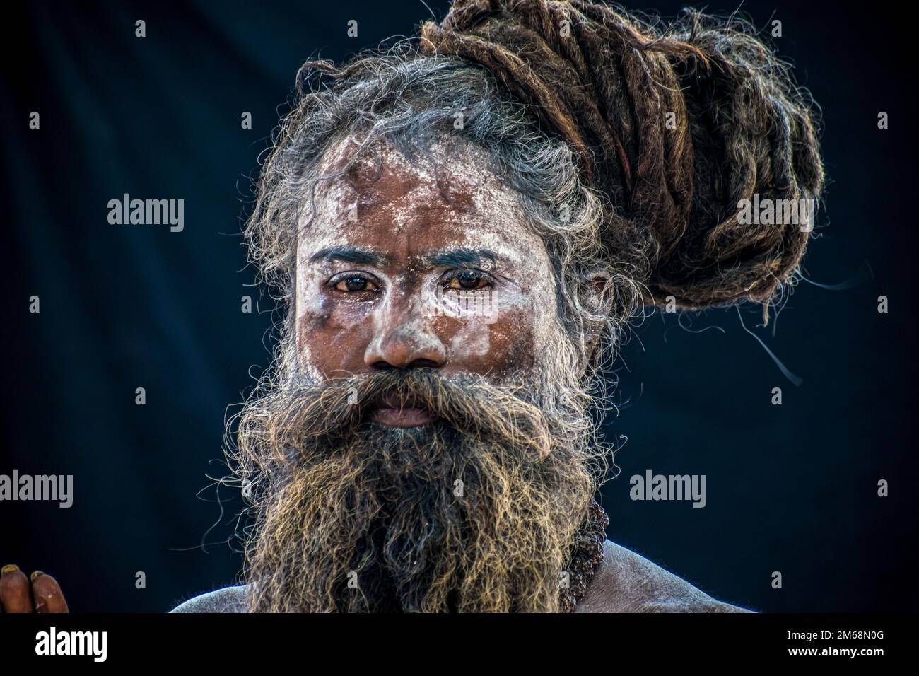 A portrait of a Naga Sadhu with painted face on the black background Stock Photo