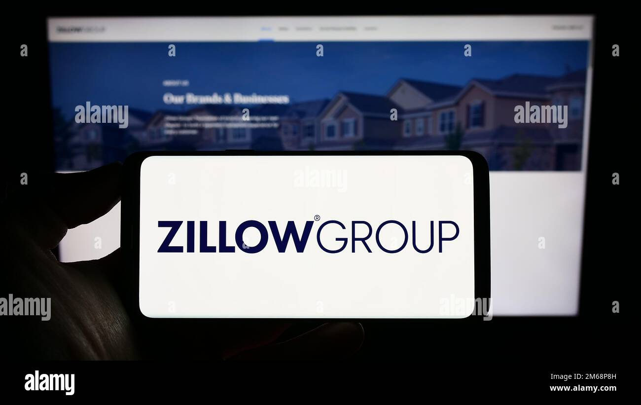 Person holding cellphone with logo of US real estate company Zillow