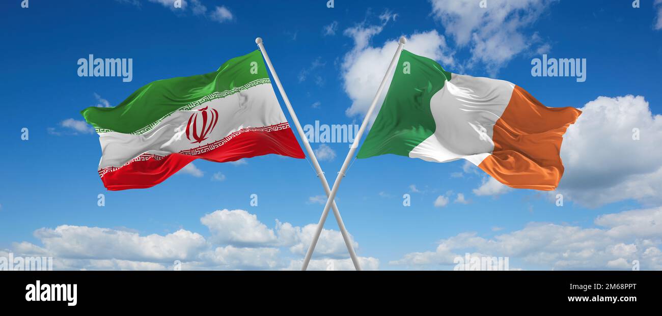 two crossed flags Ireland and Iran waving in wind at cloudy sky ...