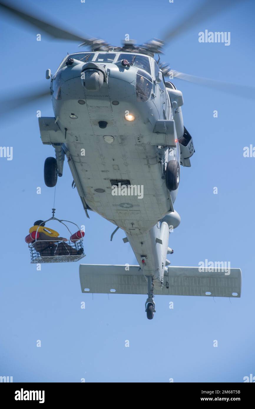 220419-N-EV253-1630 SAN DIEGO (April 19, 2022) – A U.S. Marine, assigned to 1st Marine Division, is hoisted to an MH-60S Seahawk helicopter, assigned to the “Wildcards” of Helicopter Sea Combat Squadron (HSC) 23 via rescue basket during a personnel recovery event off the coast of Camp Pendleton, California April 19, 2022. During the evolution, which was overseen by HSC-3, the Chief of Naval Operations (CNO) Search and Rescue Model Manager (SARMM), HSC-23 participated in a dynamic proof-of-concept event in which two MH-60S helicopters conducted search and rescue operations to recover large troo Stock Photo
