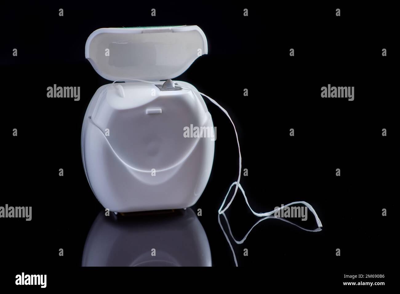 Container with dental floss. Floss on black background. White dental