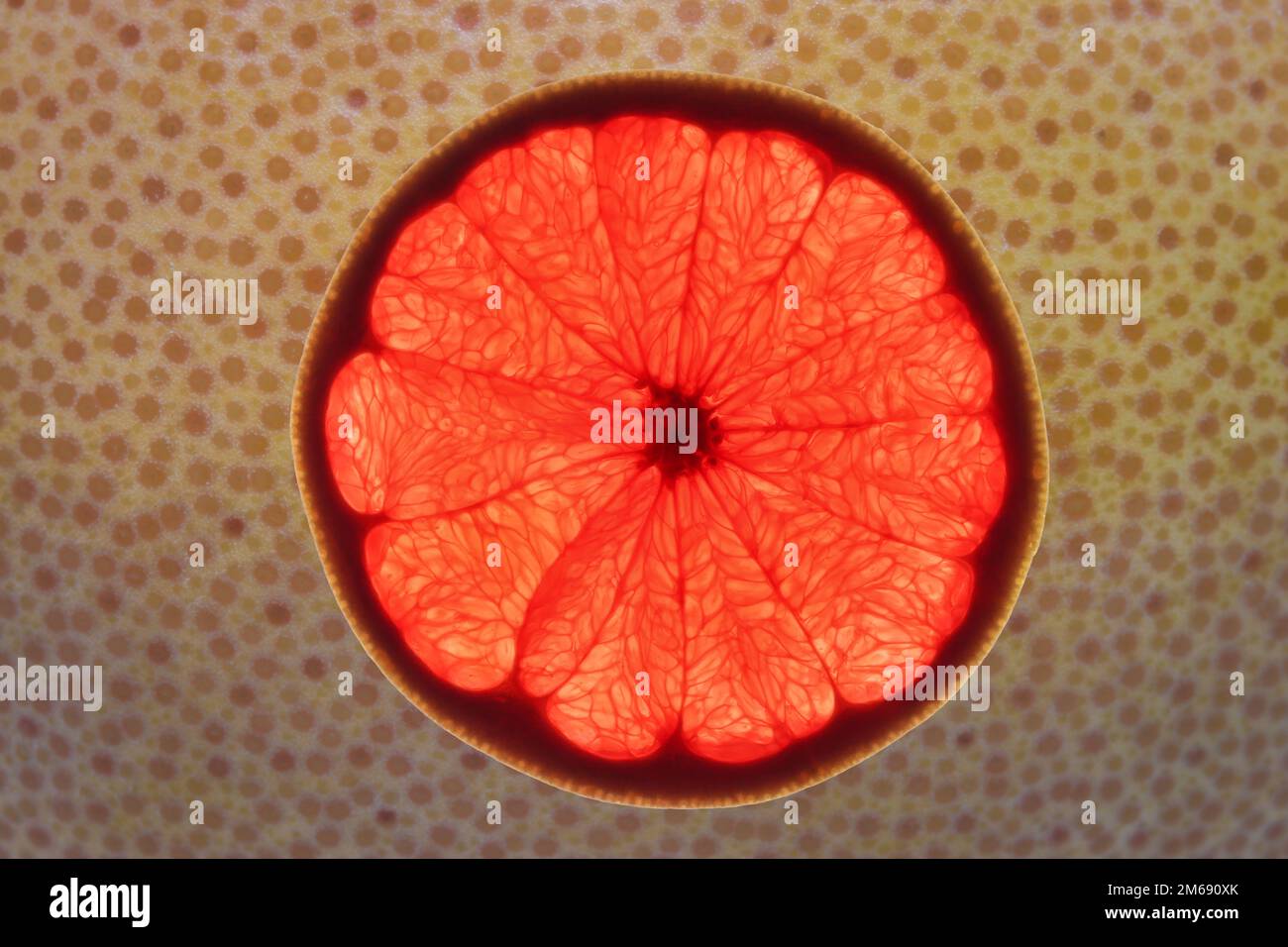 Slice of ripe ruby grapefruit on its peel abstract background Stock Photo