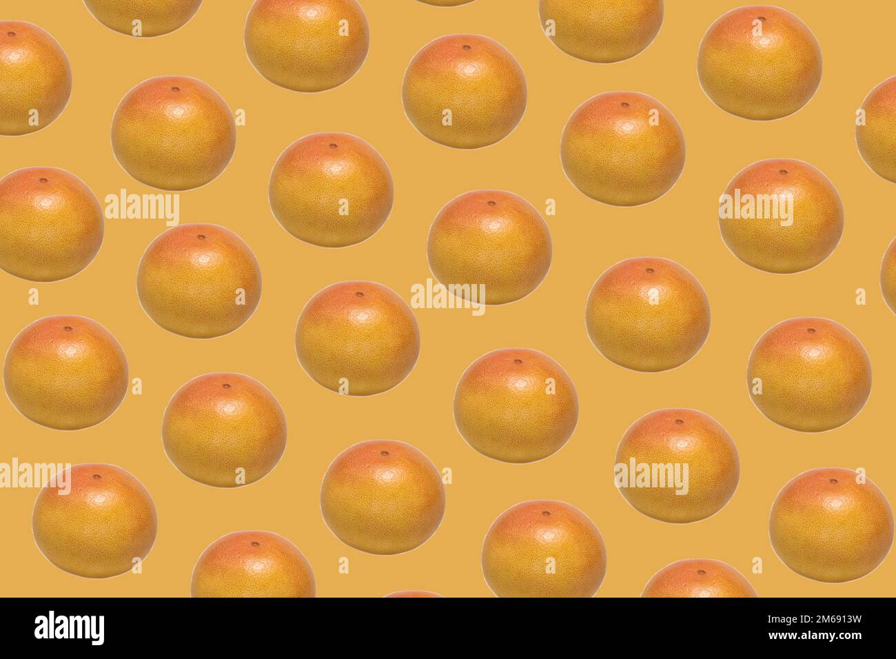 Pattern made of whole ripe ruby grapefruit on yellow background Stock Photo