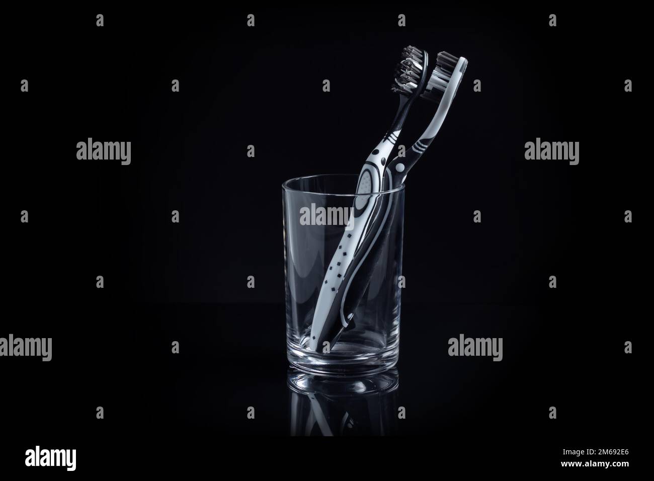 Two toothbrushes in a glass with copy space on black Stock Photo - Alamy