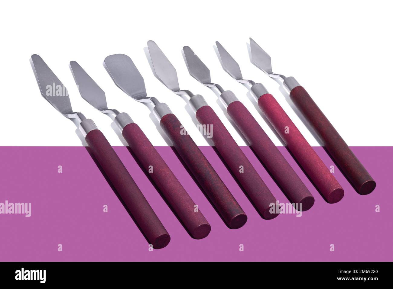 A set of palette knives lies on a white-purple background. Close-up. Stock Photo