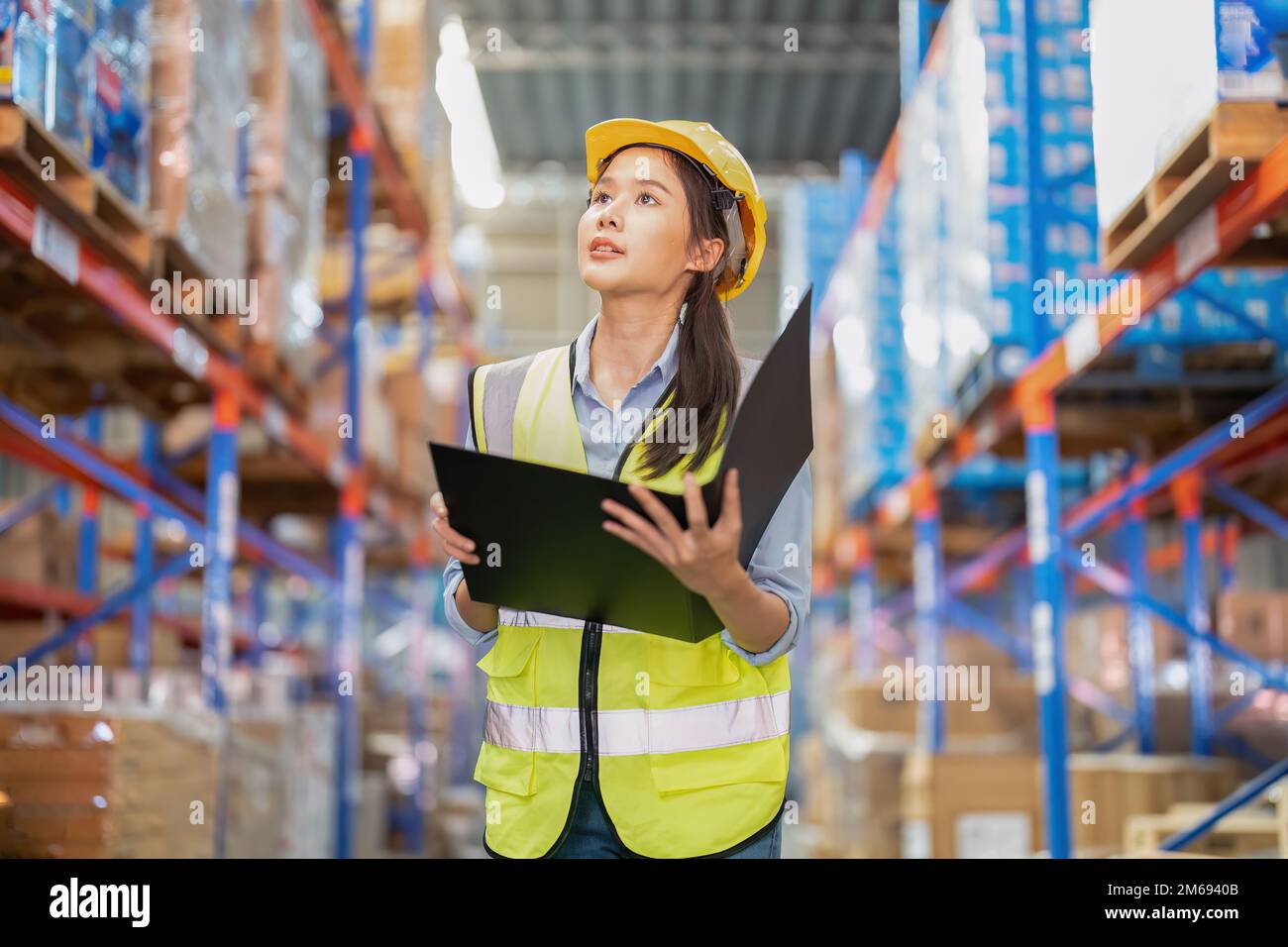 Staff working in large depot storage warehouse hold check list walking ...