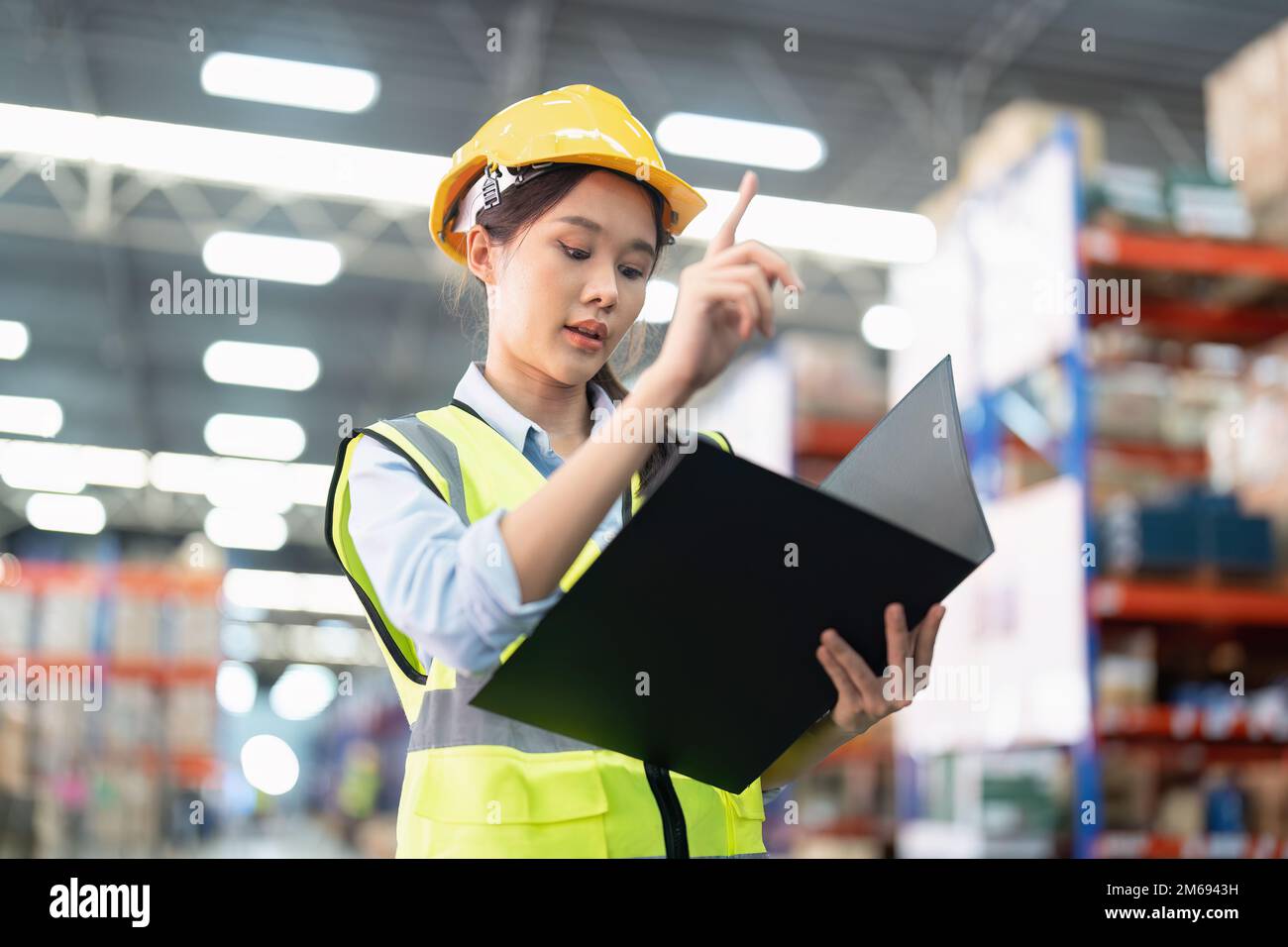 Staff working in large depot storage warehouse hold check list walking ...