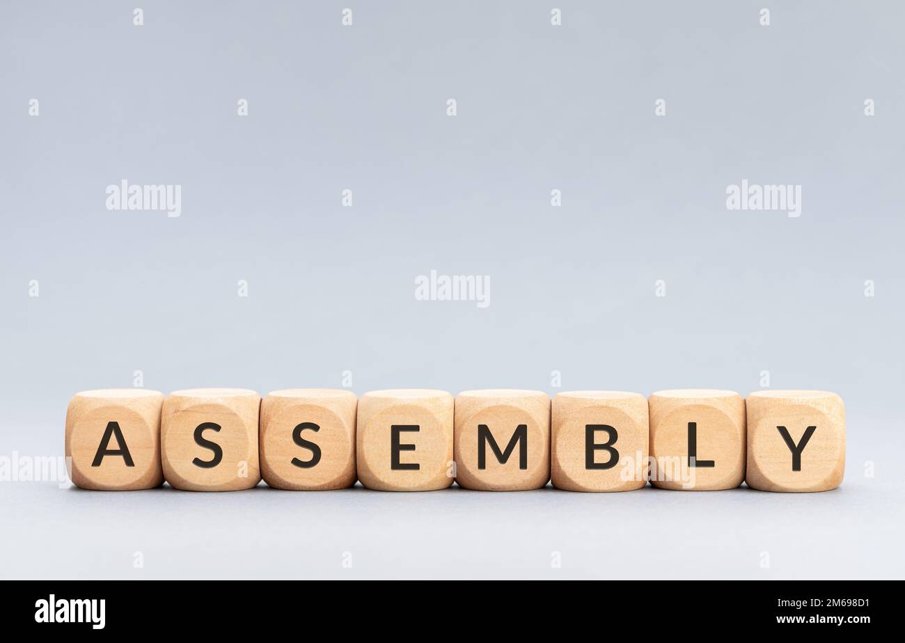 Assembly word on wooden blocks on gray background. Copy space Stock Photo