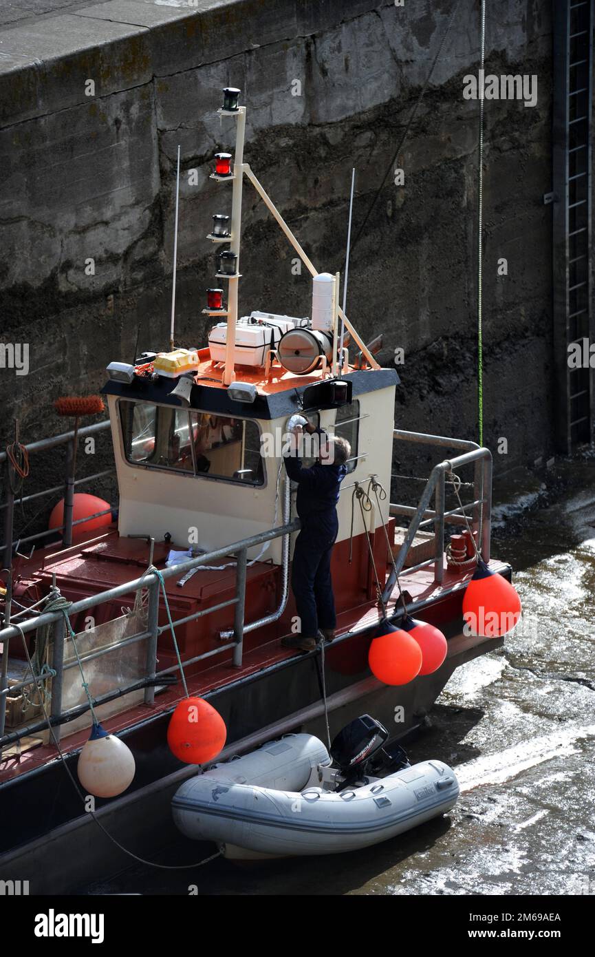 A fisherman works on his boat in the harbour in Padstow, Cornwall UK. Stock Photo