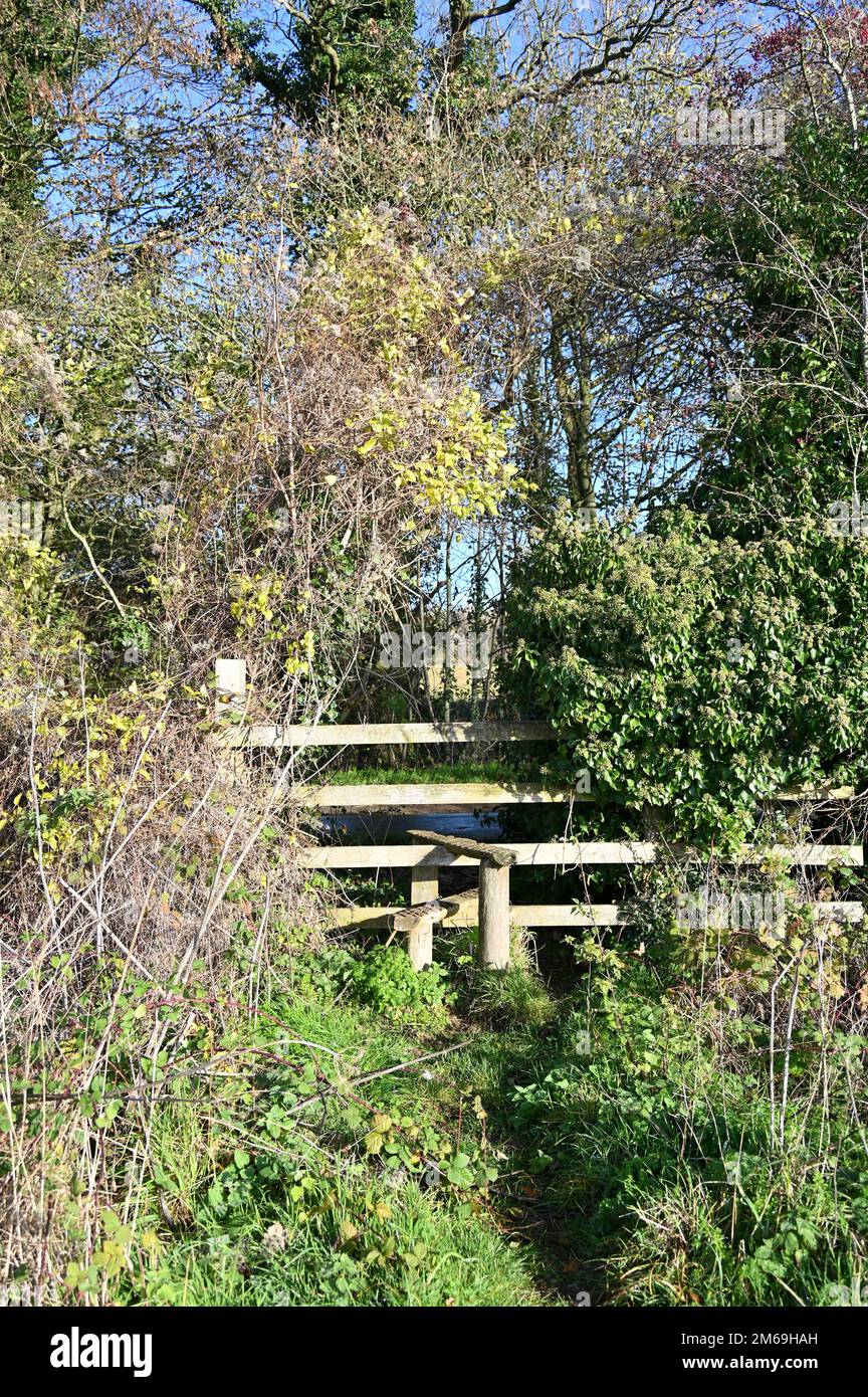 A stile set into a hedge on a footpath leading to the north Oxfordshire village of Swerford Stock Photo