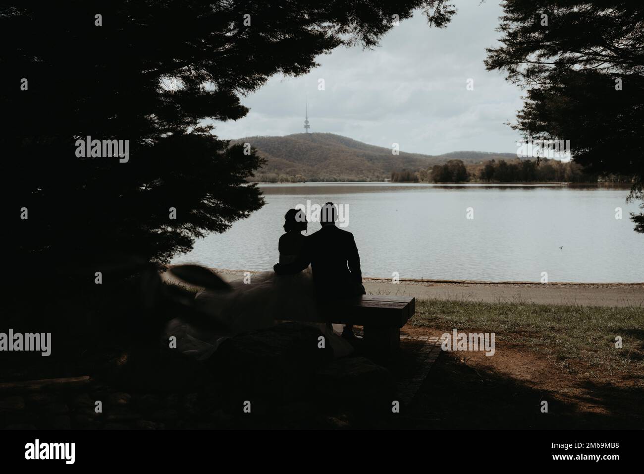 A groom and bride sitting on a bench on the lakeside Stock Photo - Alamy