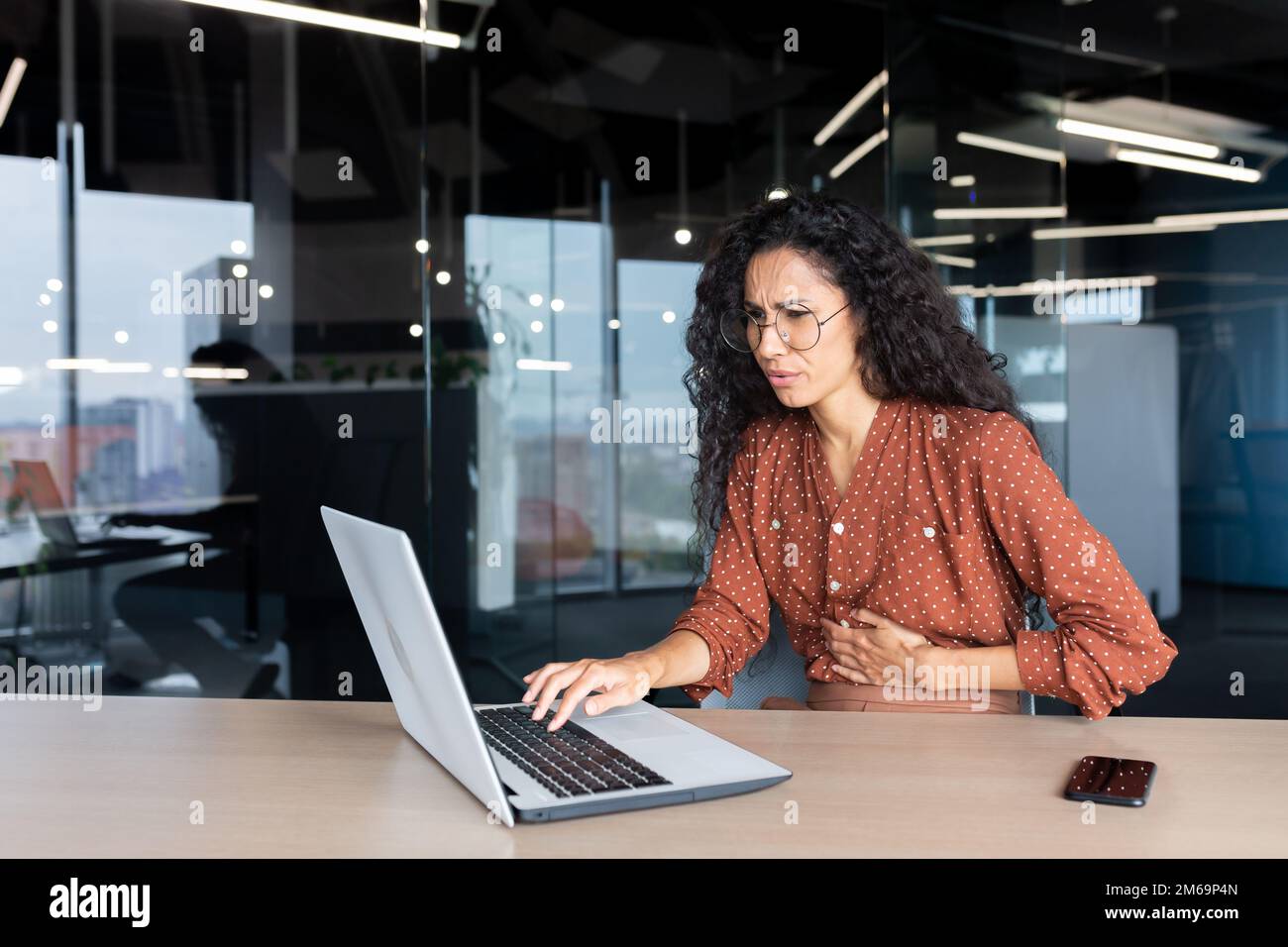 Sick business woman working inside office using laptop while sitting at