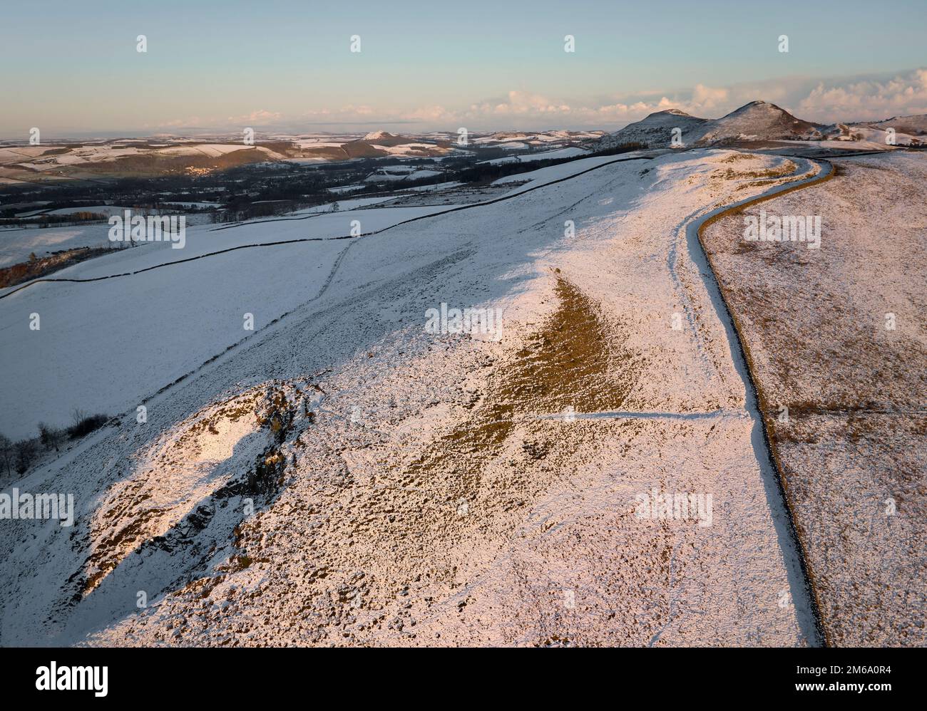 Aerial shot of Cauldhiels Hillfort with details picked up by snow and low winter sun with The Eildons in the background. Stock Photo