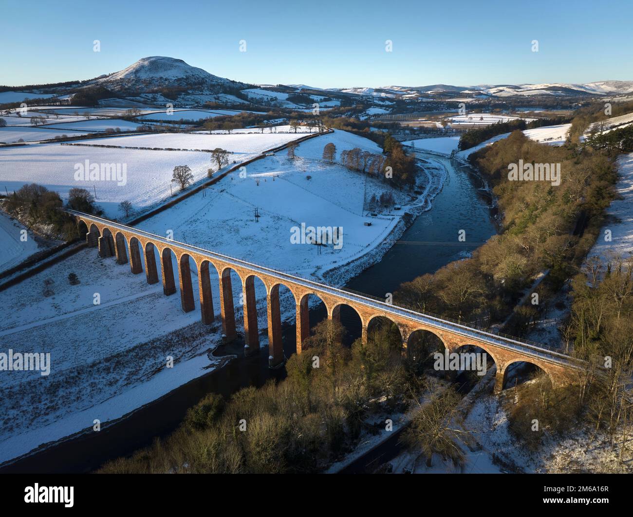 Aerial view of the Leaderfoot Viaduct crossing the River Tweed with the remains of Trimontium Roman Camp towards The Eildons on a snowy winter day. Stock Photo