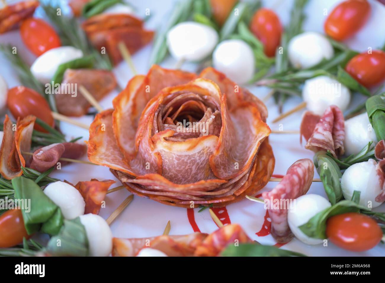 A display of ham shaped as a flower surround by sticks of salami