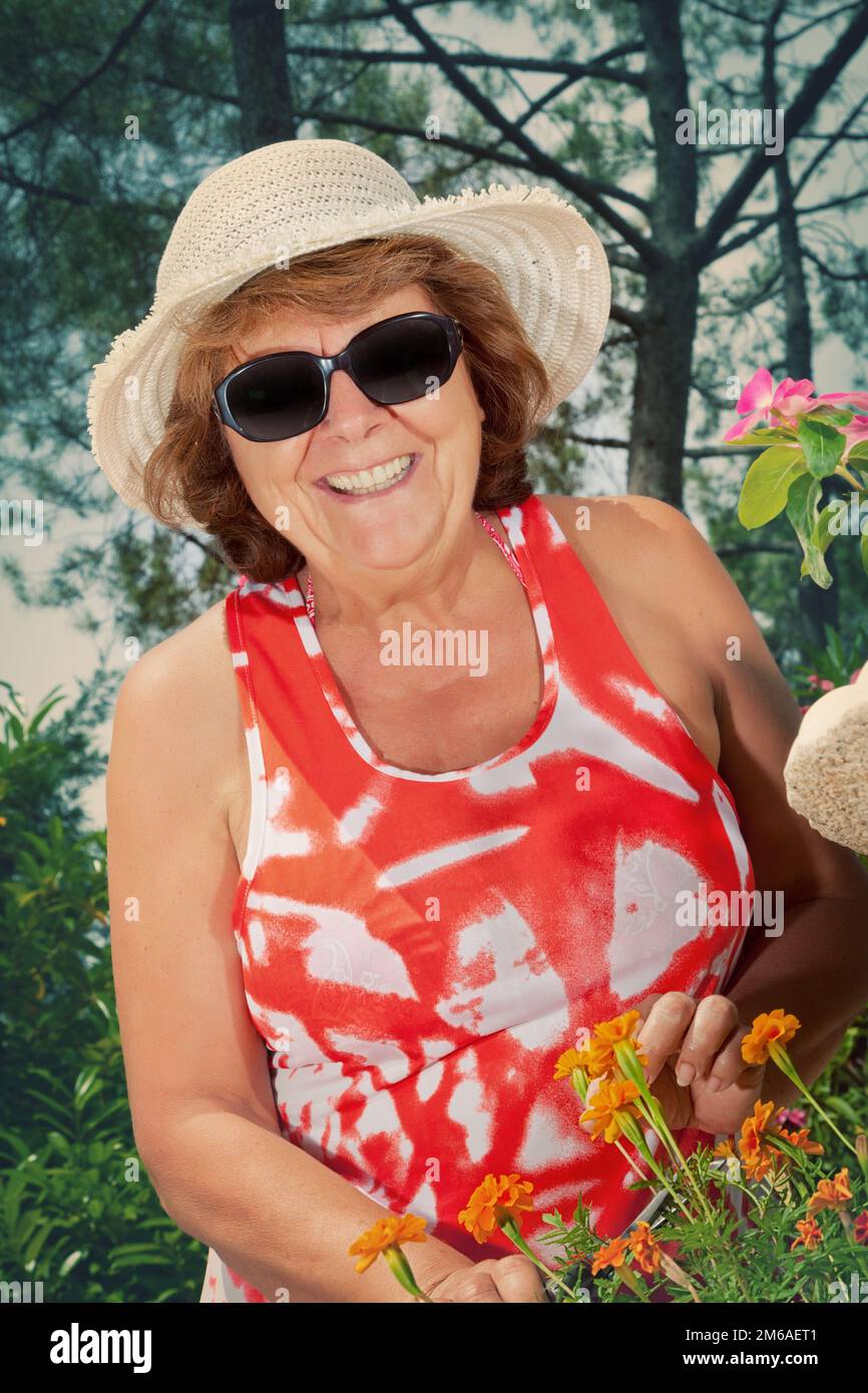 Smiling Mature Woman Pruning Flowers Stock Photo