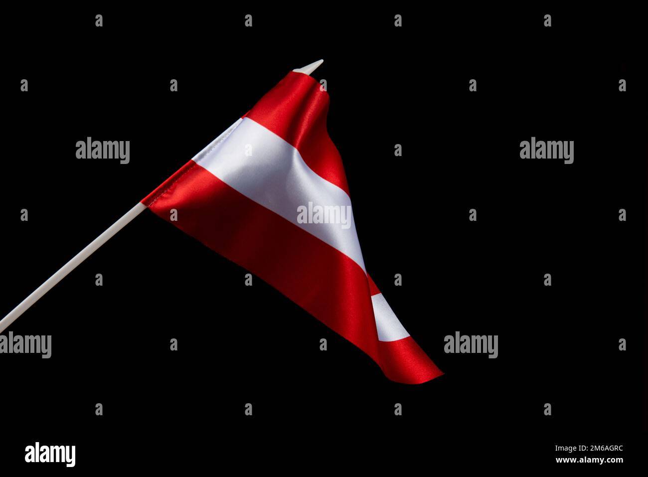 The Latvian flag on a black background is developing and flying in the wind Stock Photo