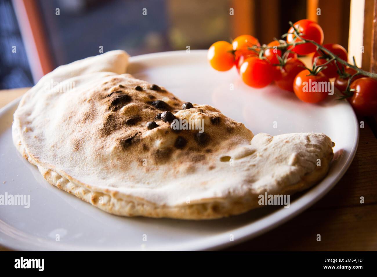 Calzone Pizza. Neapolitan pizza stuffed with cheese, tomato and other ingredients such as meat or vegetables. Authentic Italian recipe. Stock Photo