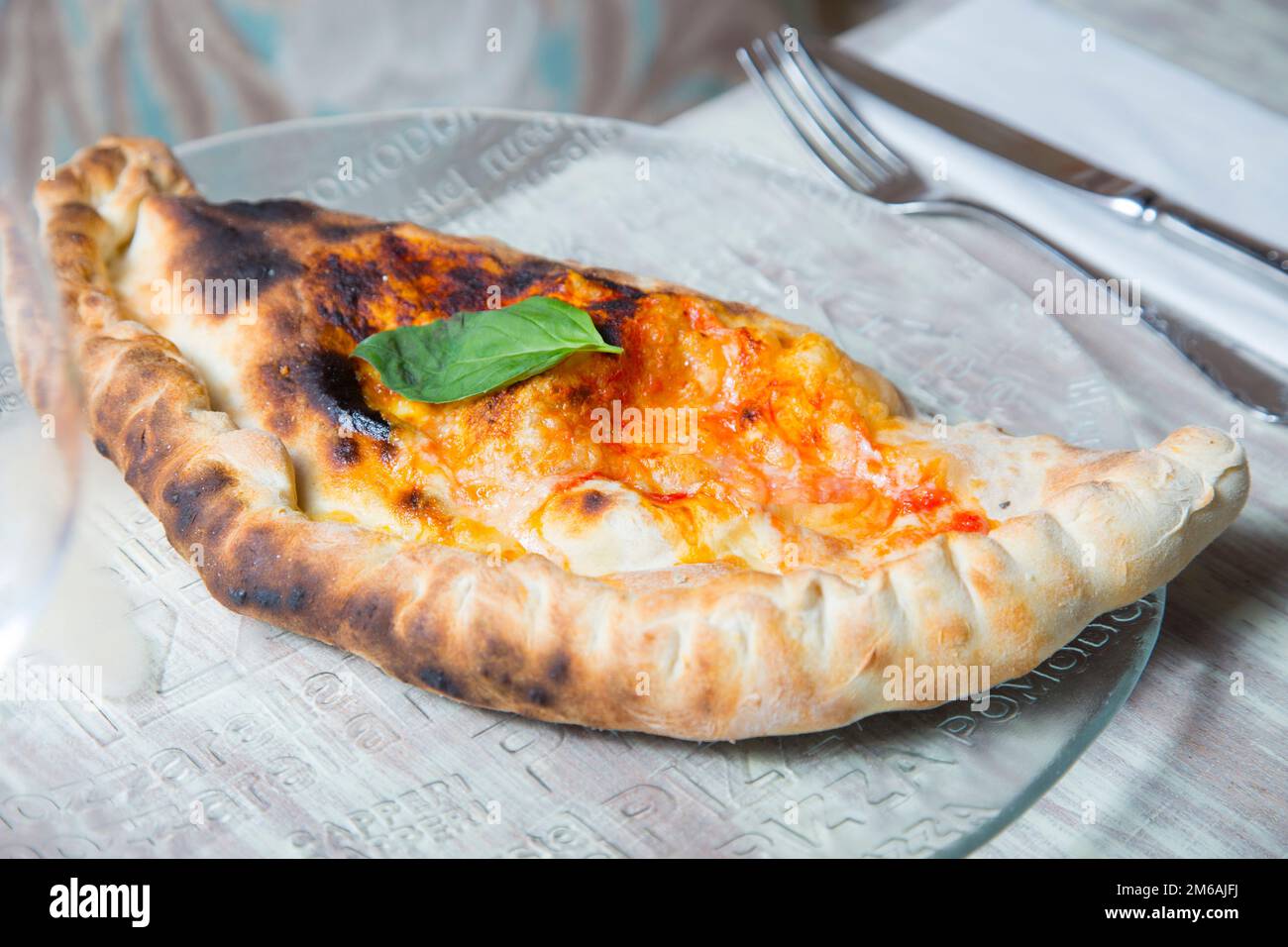 Calzone Pizza. Neapolitan pizza stuffed with cheese, tomato and other ingredients such as meat or vegetables. Authentic Italian recipe. Stock Photo