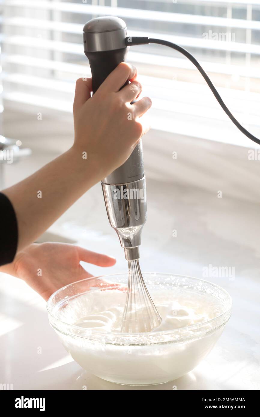female hands using electric mixer to make whipped cream Stock Photo Alamy
