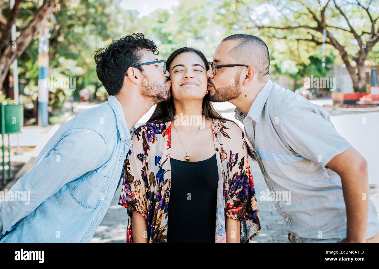 Love triangle concept. Polygamy concept. Two men kissing a girl cheek. Portrait of two guys